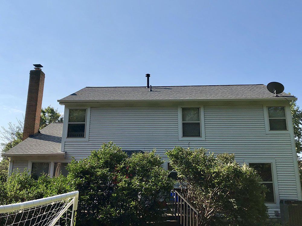 The back of a white house with a satellite dish on the roof.