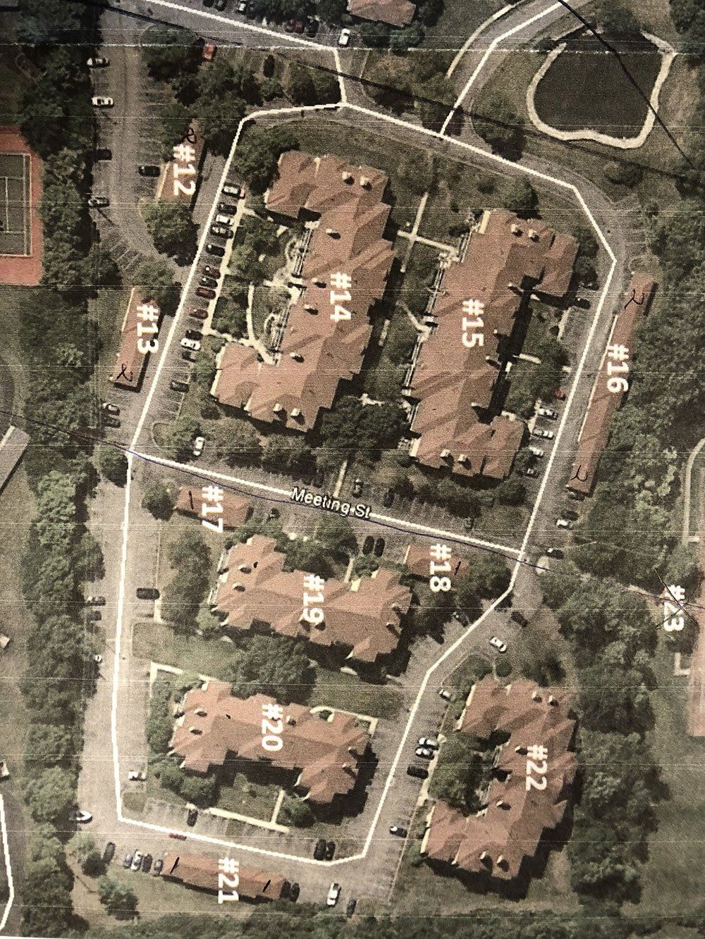 An aerial view of a residential area with a tennis court in the background