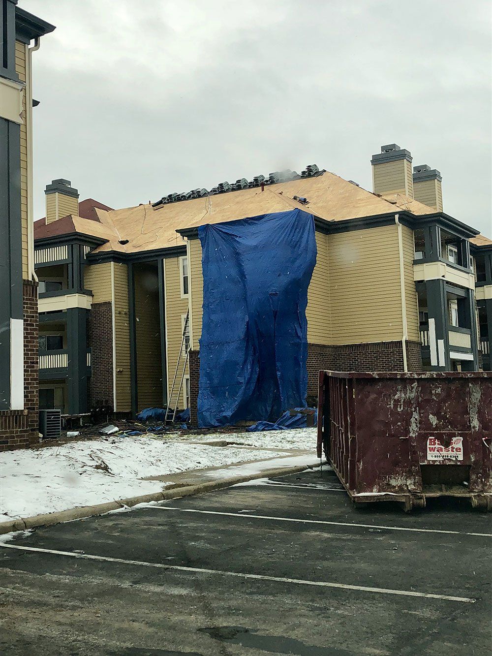 A building with a blue tarp on the roof is being remodeled.
