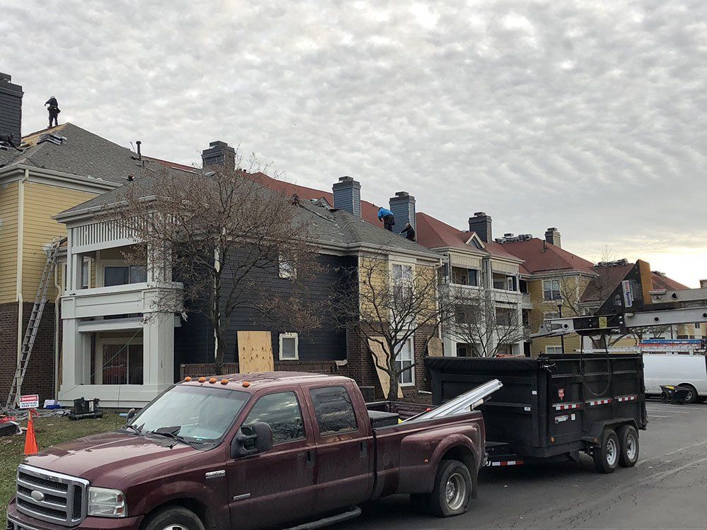 A truck with a trailer attached to it is parked in front of a row of houses.