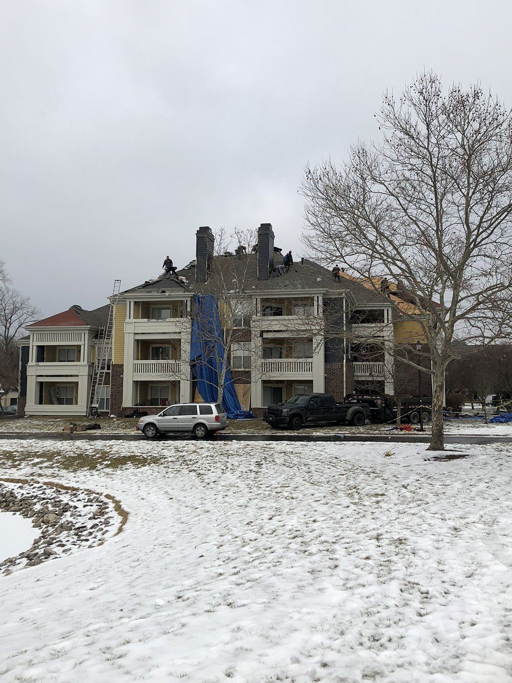 A snowy field with cars parked in front of a building.
