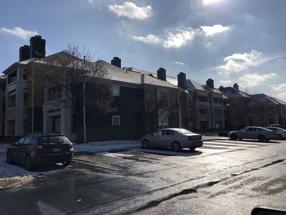 A parking lot with cars parked in front of a row of buildings.