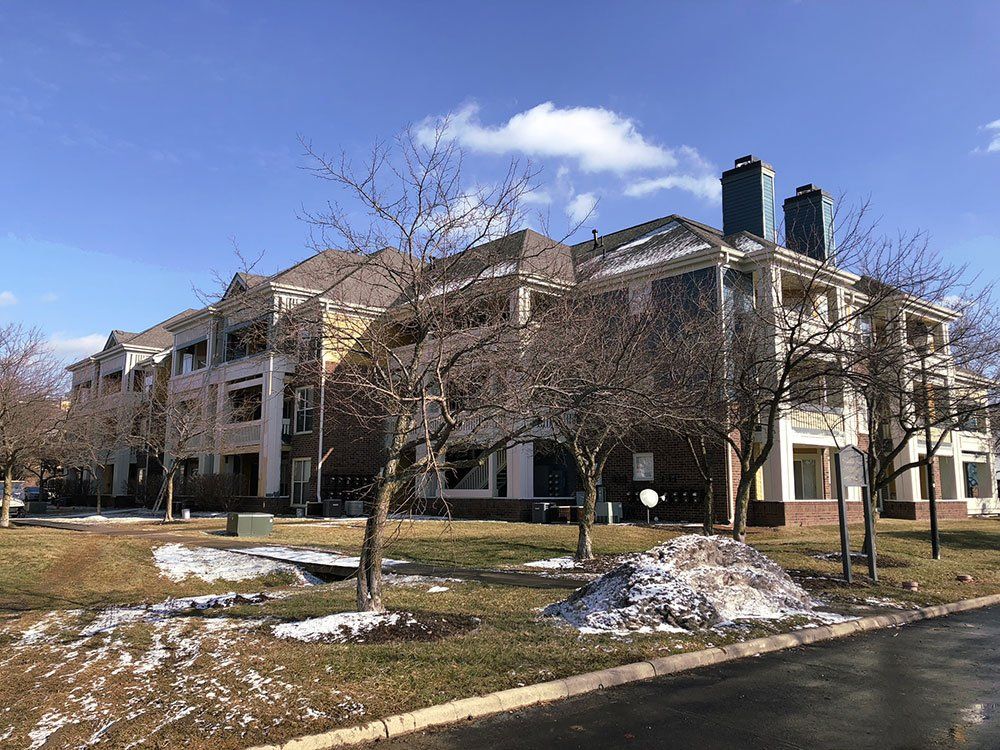 A large apartment building with trees in front of it on a sunny day.