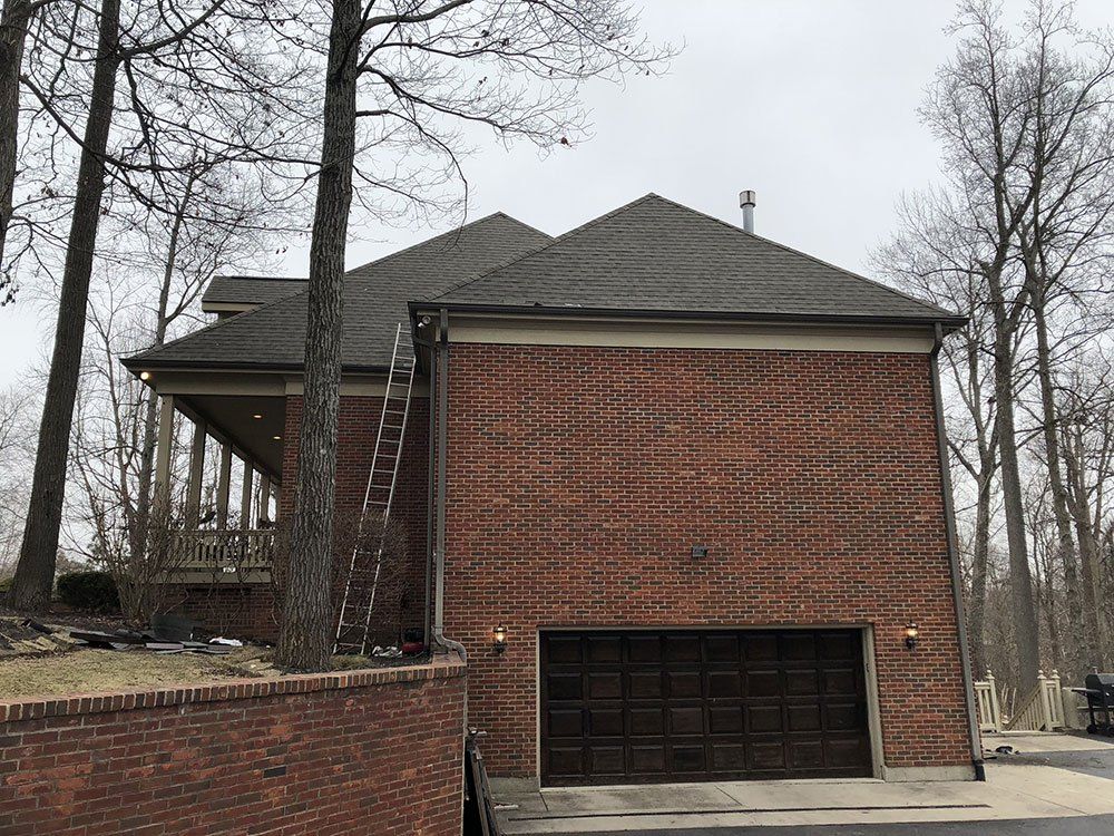 A large brick house with a garage and a ladder on the side of it.