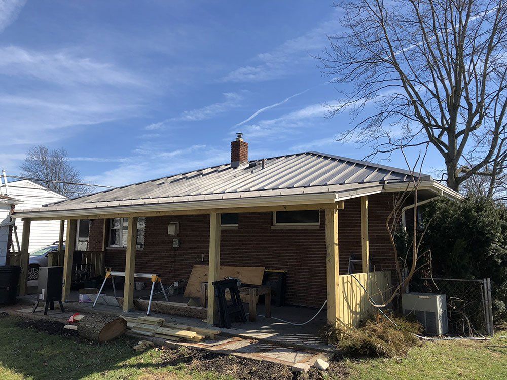 A brick house with a metal roof and a porch.