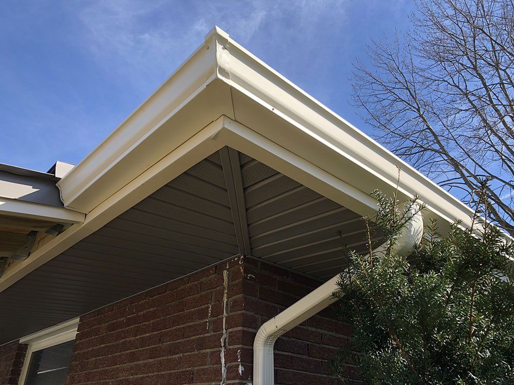 A white gutter on the side of a brick house.