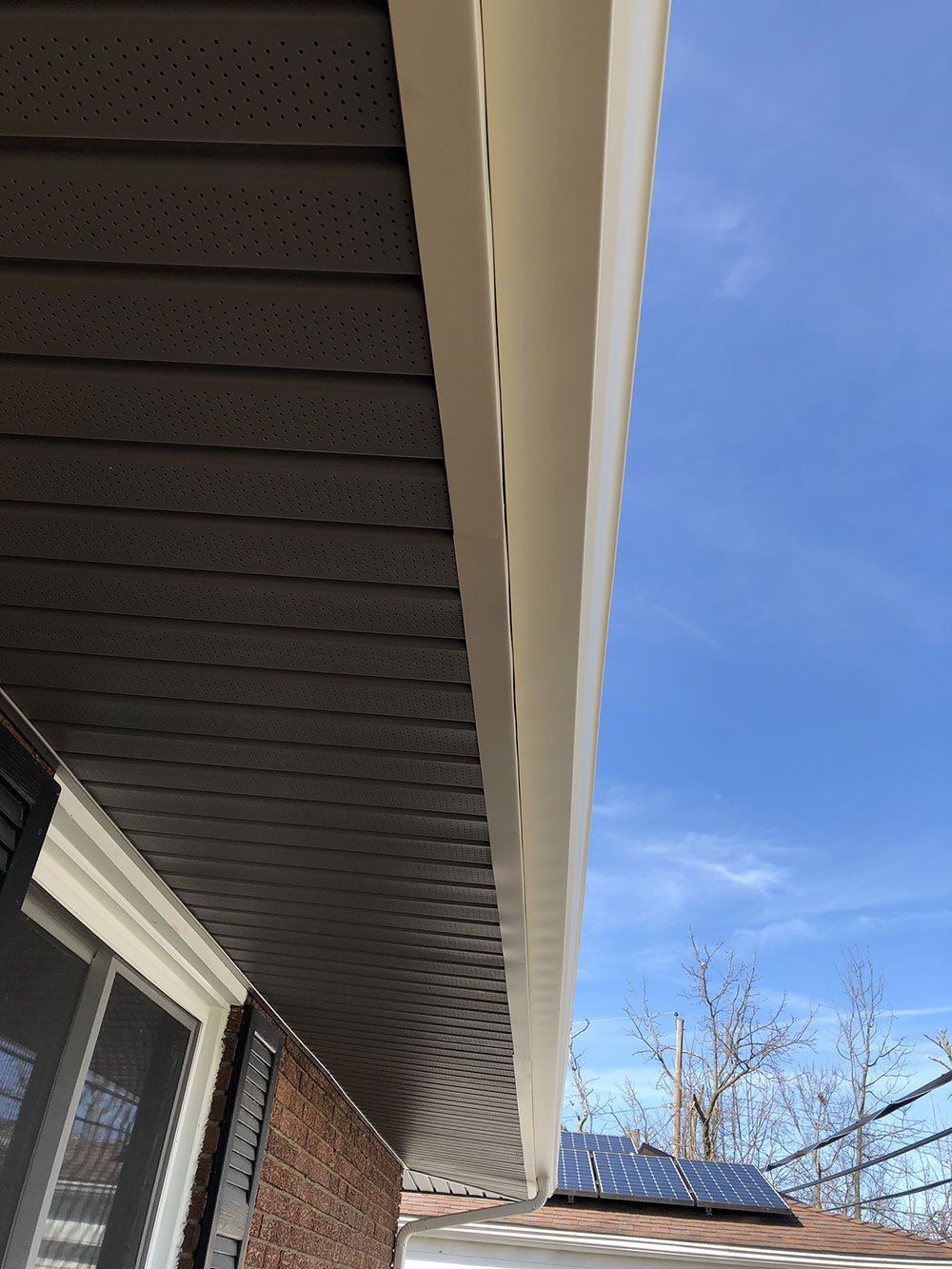 Looking up at the roof of a house with a blue sky in the background.