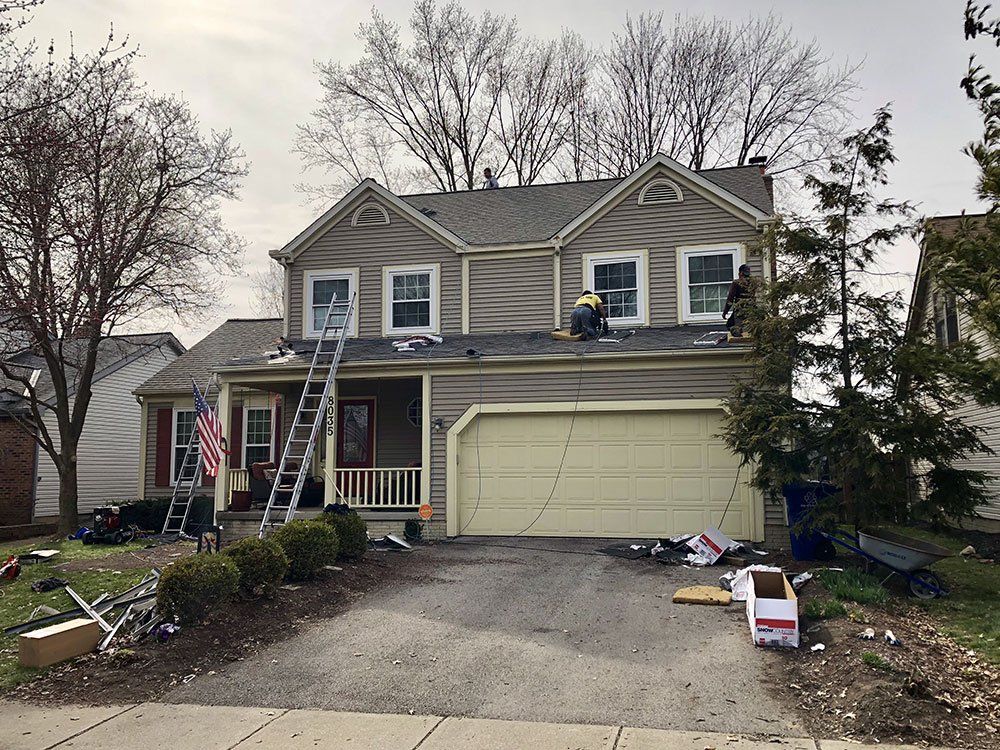 Two men are working on the roof of a house.