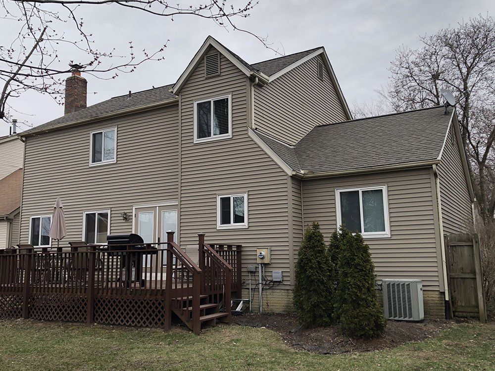 The back of a house with a large deck and stairs.