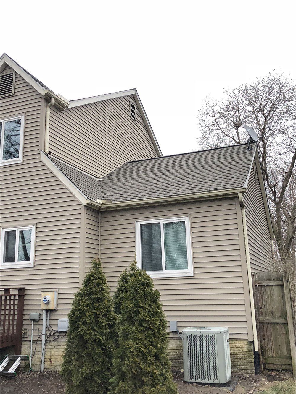 The back of a house with a roof and a lot of windows.