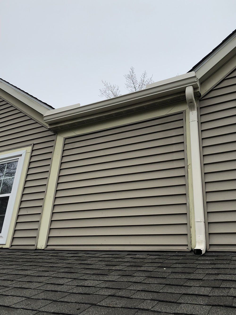 A house with a gutter on the side of it and a window.
