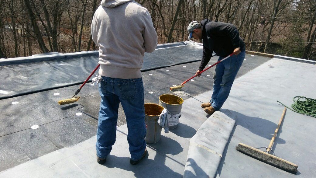 Two men are cleaning a roof with brushes and buckets