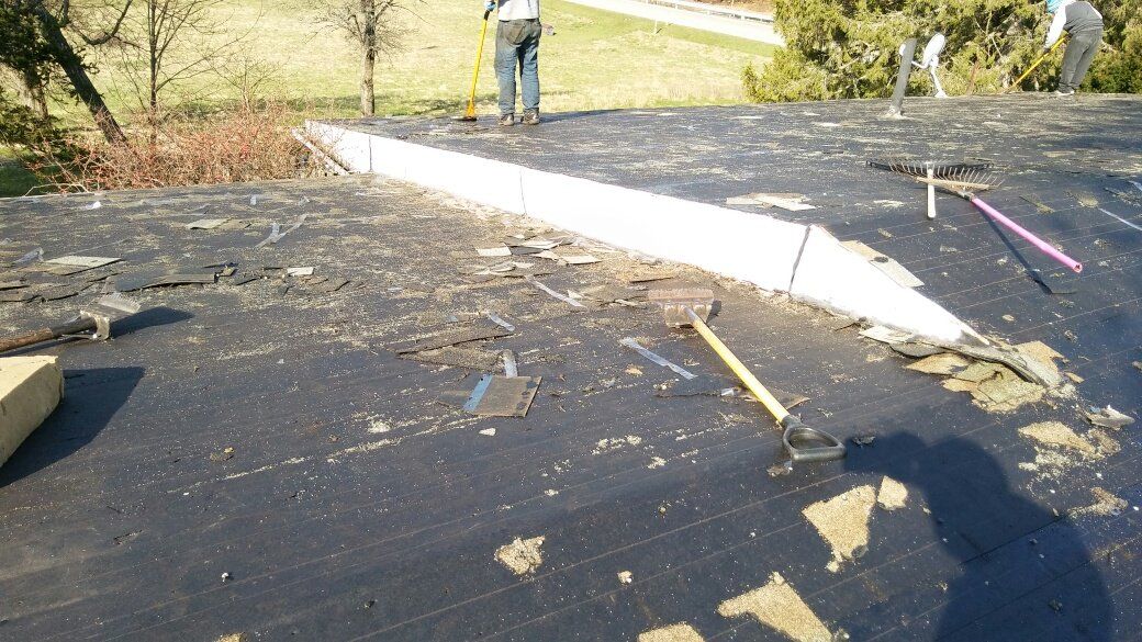 A person is working on a roof with a shovel and rake.
