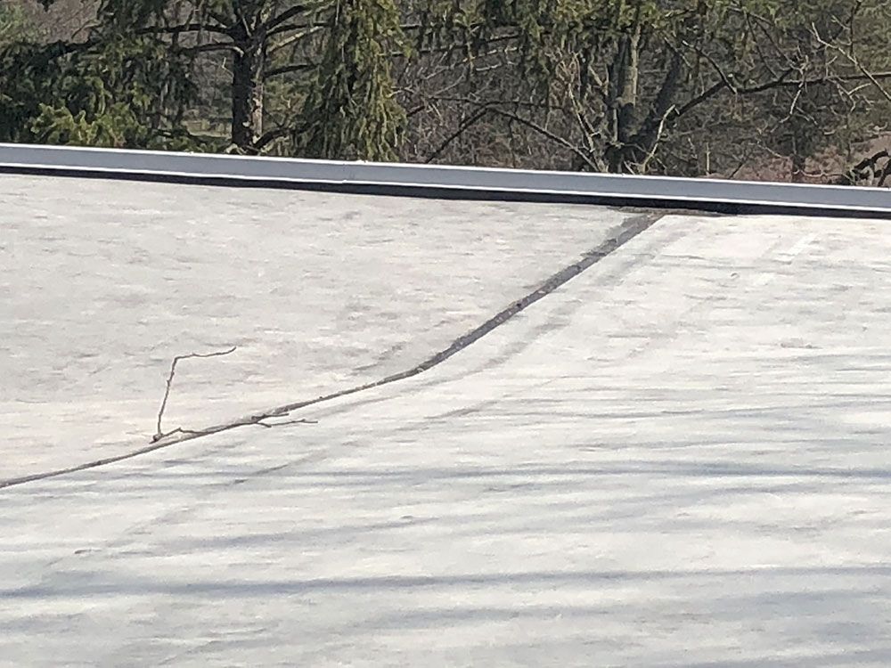 A close up of a roof with trees in the background.