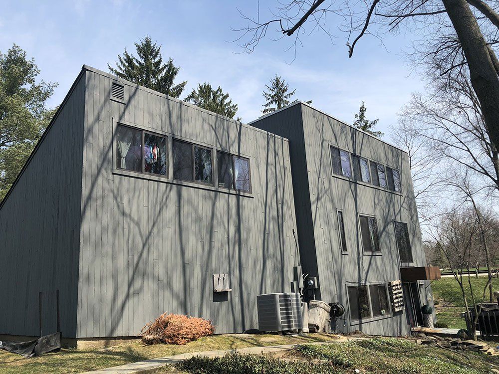 A large gray building with a lot of windows is surrounded by trees.