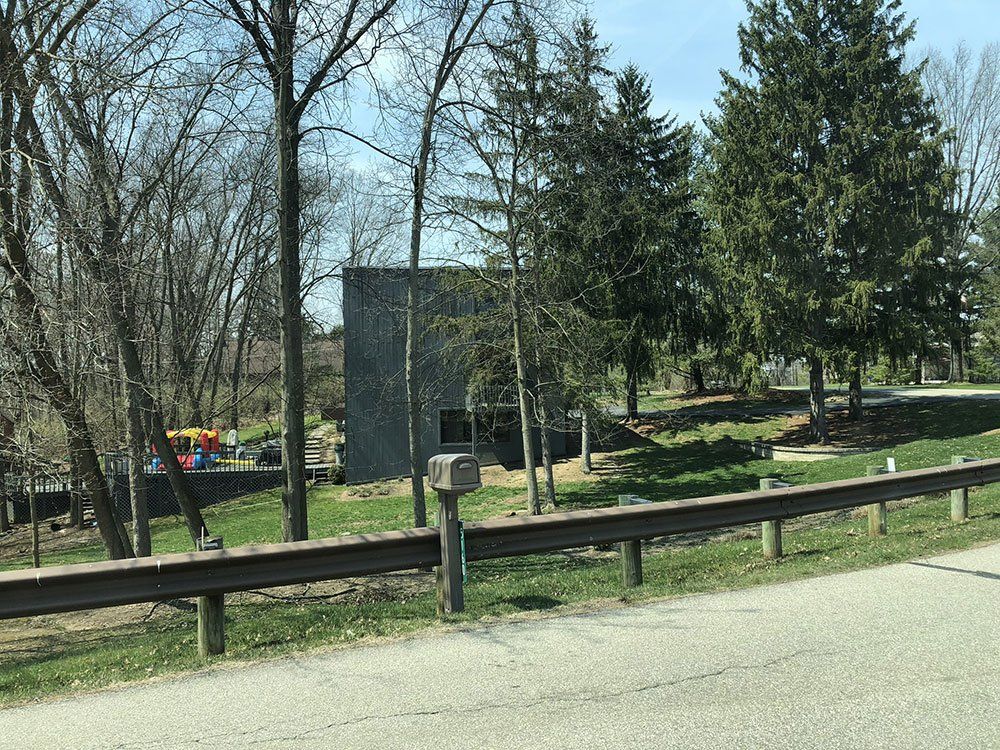 A mailbox is sitting on the side of the road next to a fence.