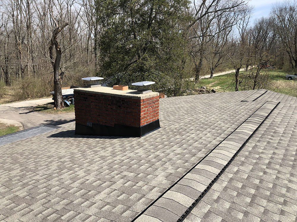 A roof with a chimney on top of it and trees in the background.