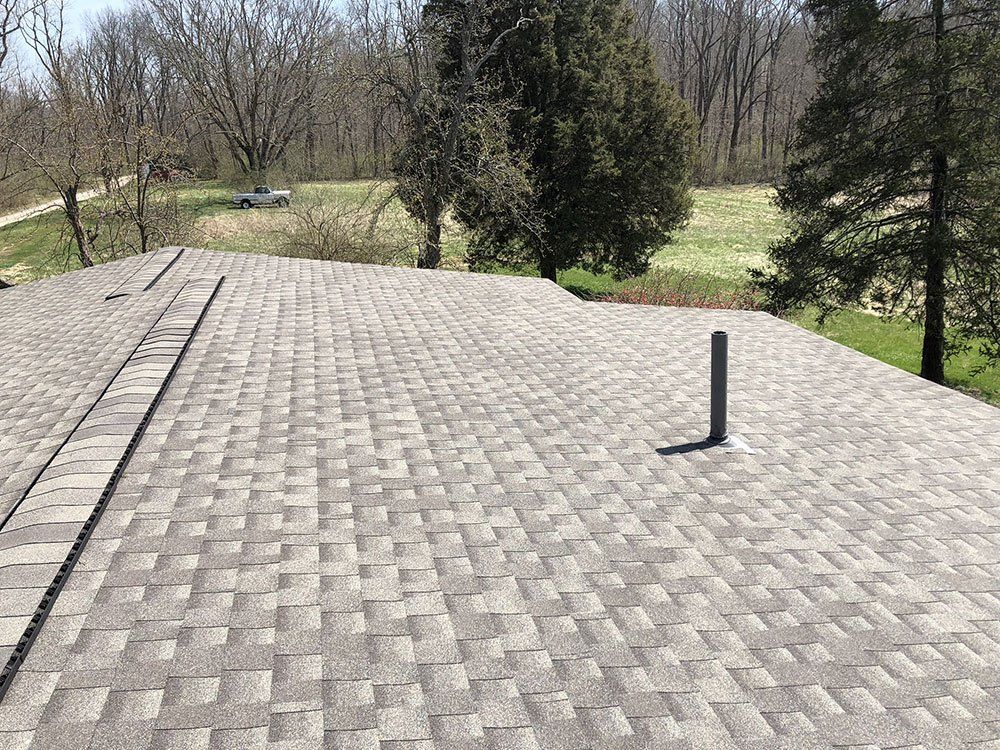 A roof with a chimney on it and trees in the background.