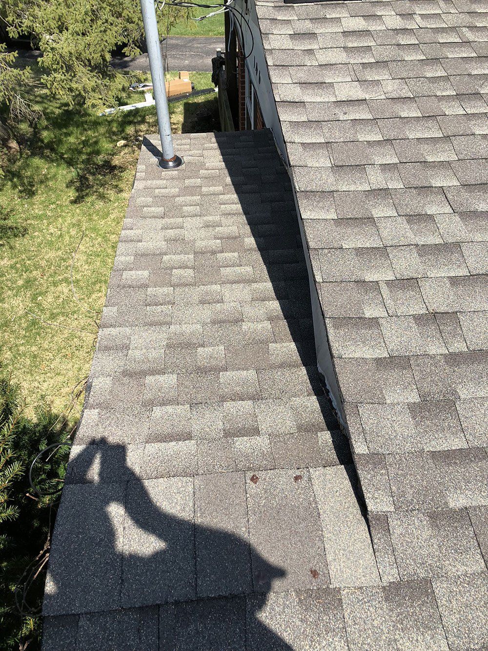 A shadow of a person is cast on the roof of a house.