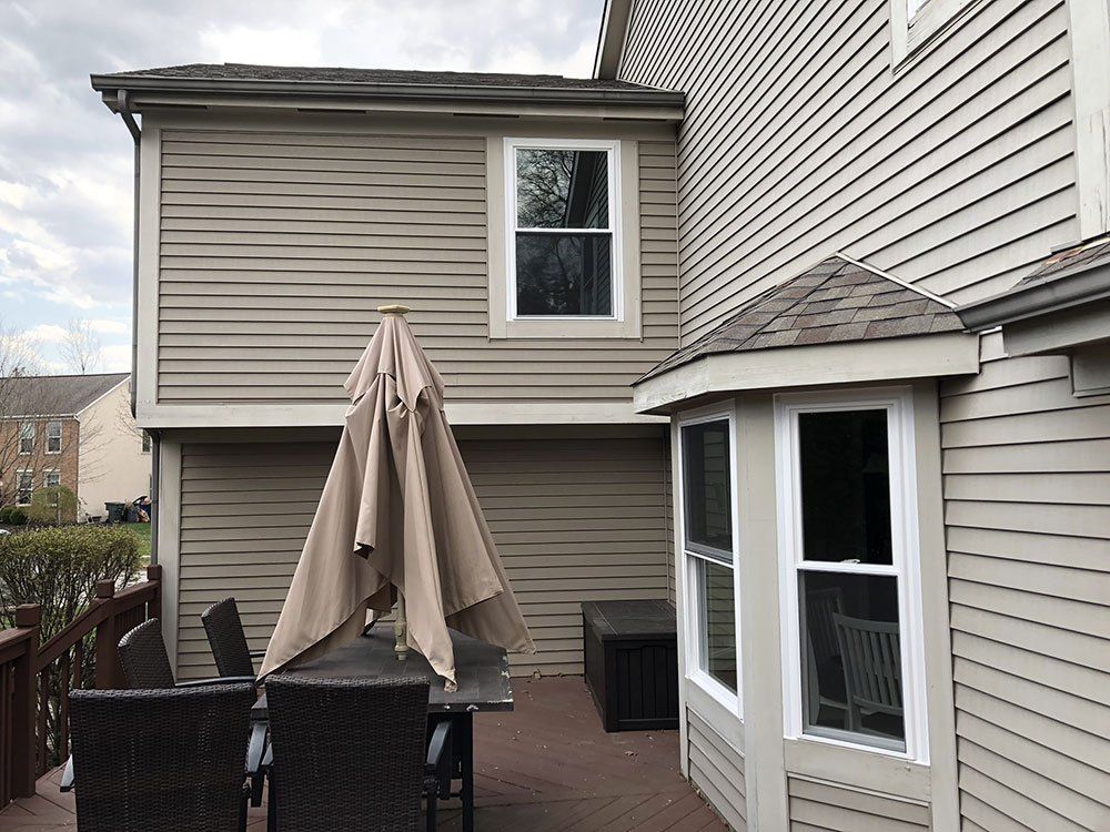 A patio with a table and chairs and an umbrella in front of a house.