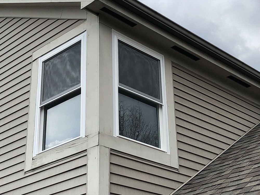 There are two windows on the side of a house.