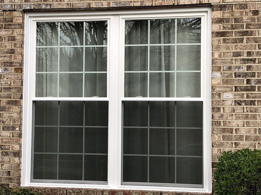 A white double hung window on a brick building.