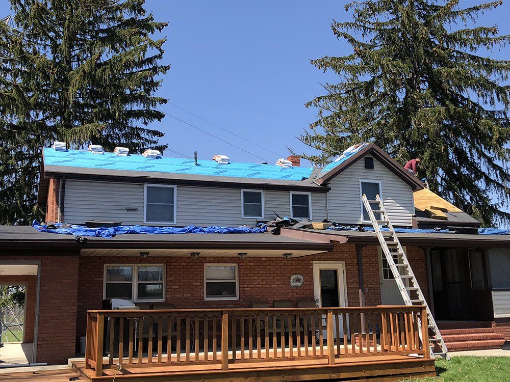 A house with a blue tarp on the roof is being remodeled.