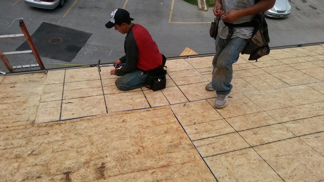 Two men are working on a roof in a parking lot.