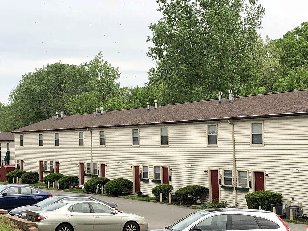 A row of apartment buildings with cars parked in front of them.