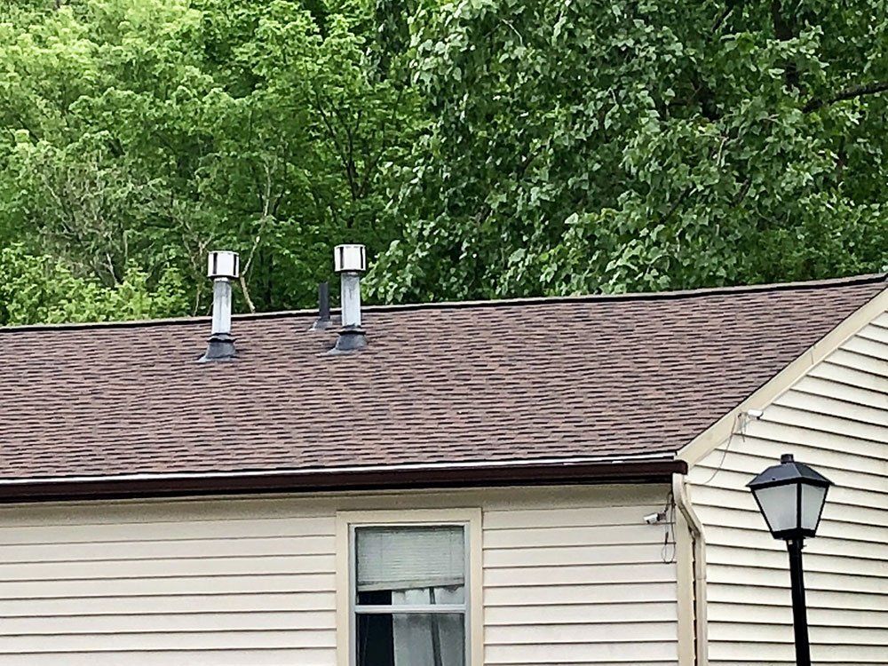 There are two chimneys on the roof of a house.