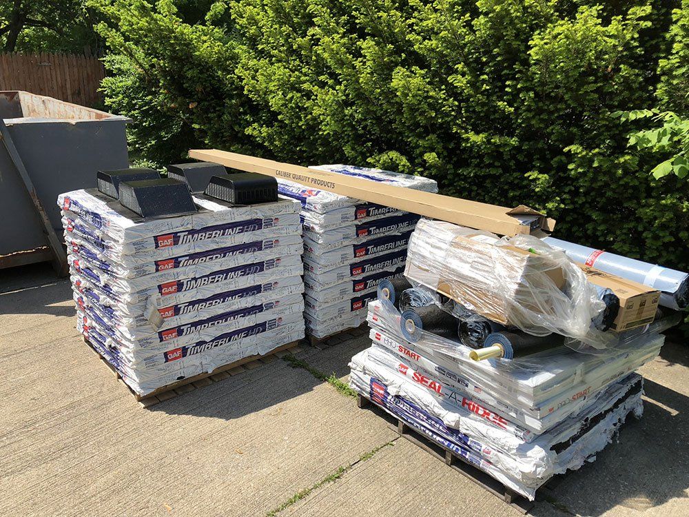 A stack of pallets filled with various types of roofing materials.