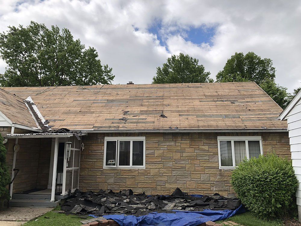 A brick house with a roof that is being removed.