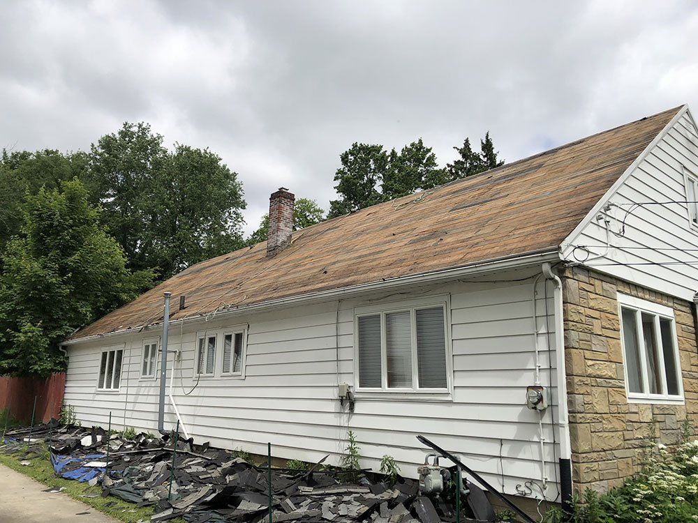 A white house with a brown roof is being demolished.