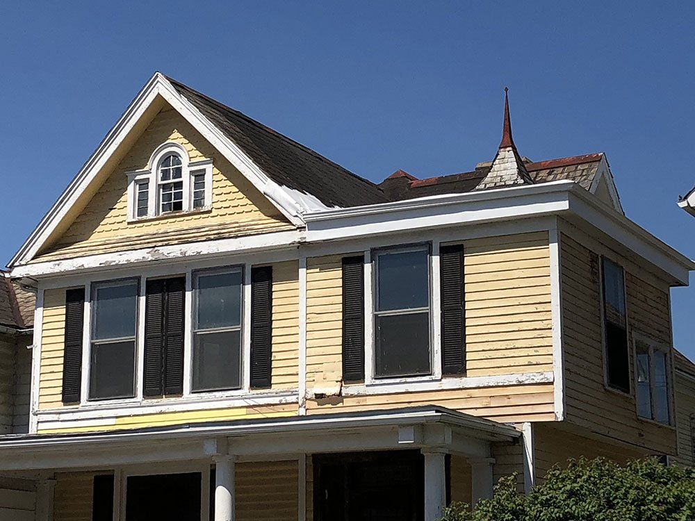 A yellow house with black shutters on the windows