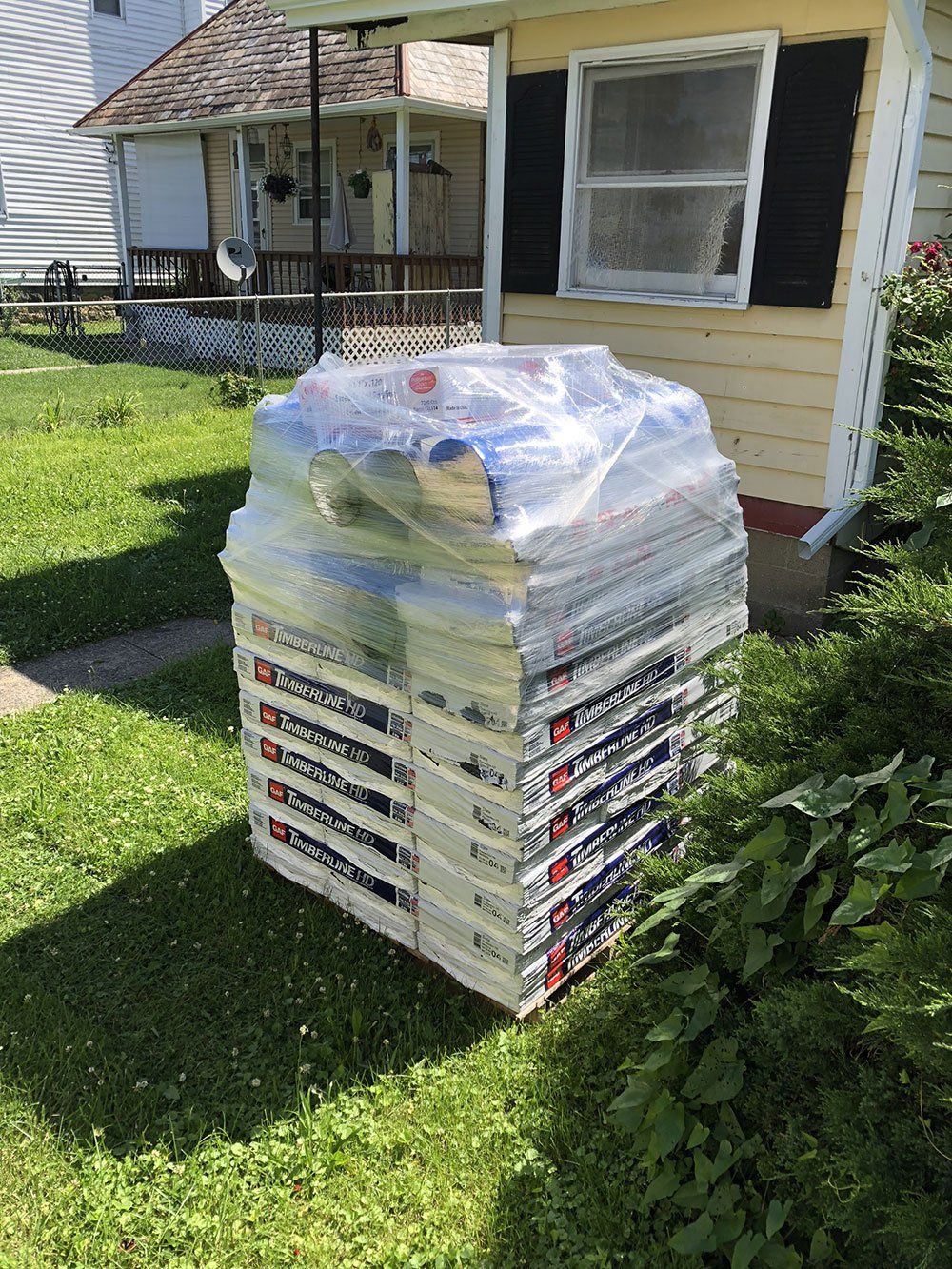 A stack of boxes sitting in the grass in front of a house.