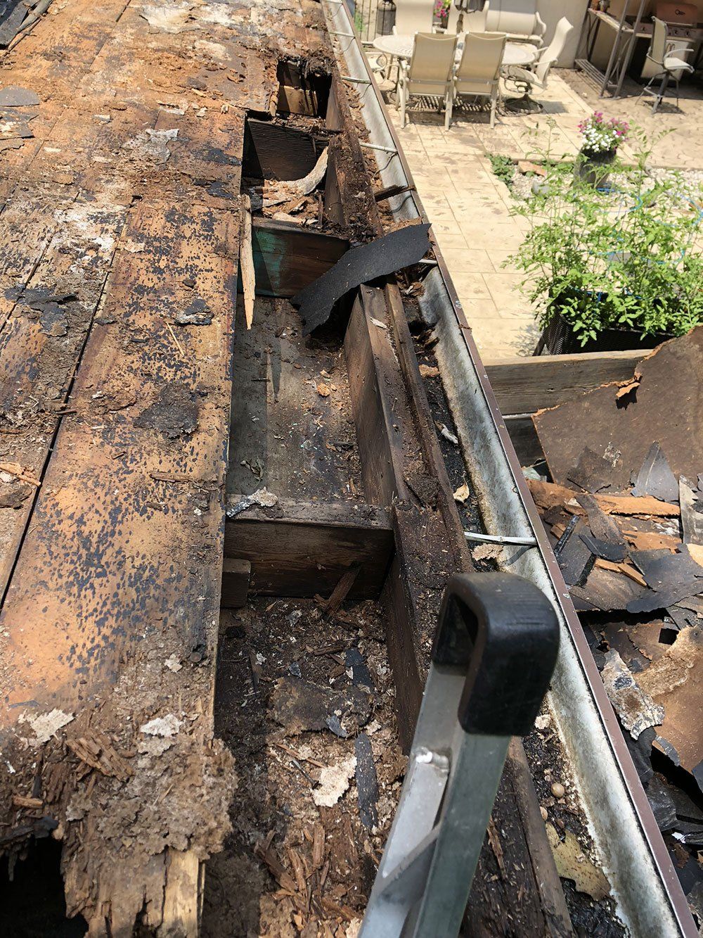 A ladder is sitting next to a wooden beam that is being removed from a roof.