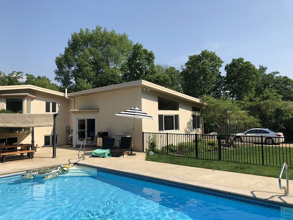 A large swimming pool is in front of a house.