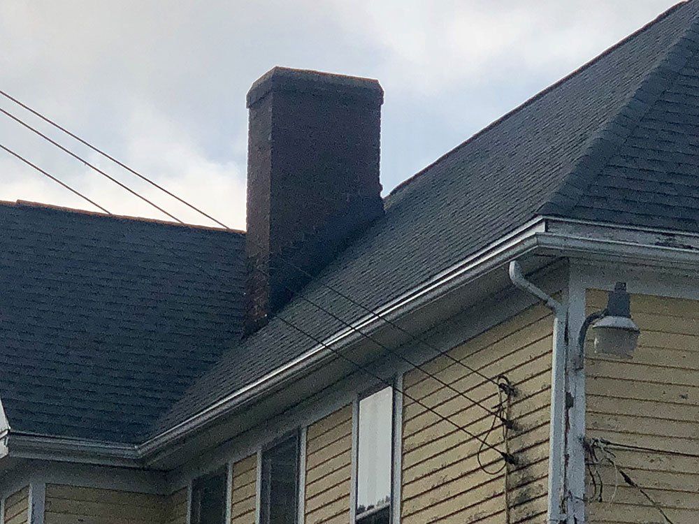 A house with a chimney on the roof and a light on the side.