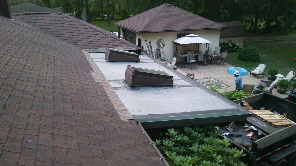 An aerial view of a roof with a house in the background.