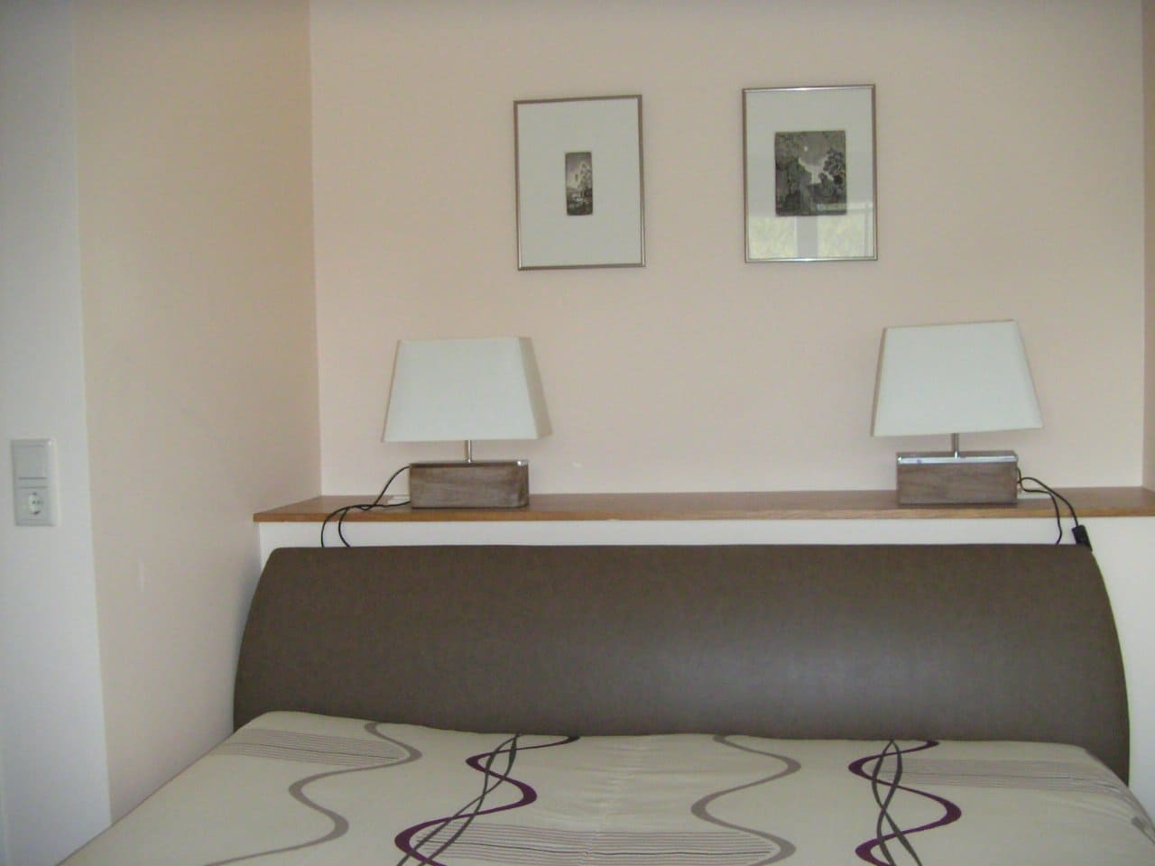 Ein Schlafzimmer mit zwei Lampen und zwei Bildern an der Wand über dem Bett