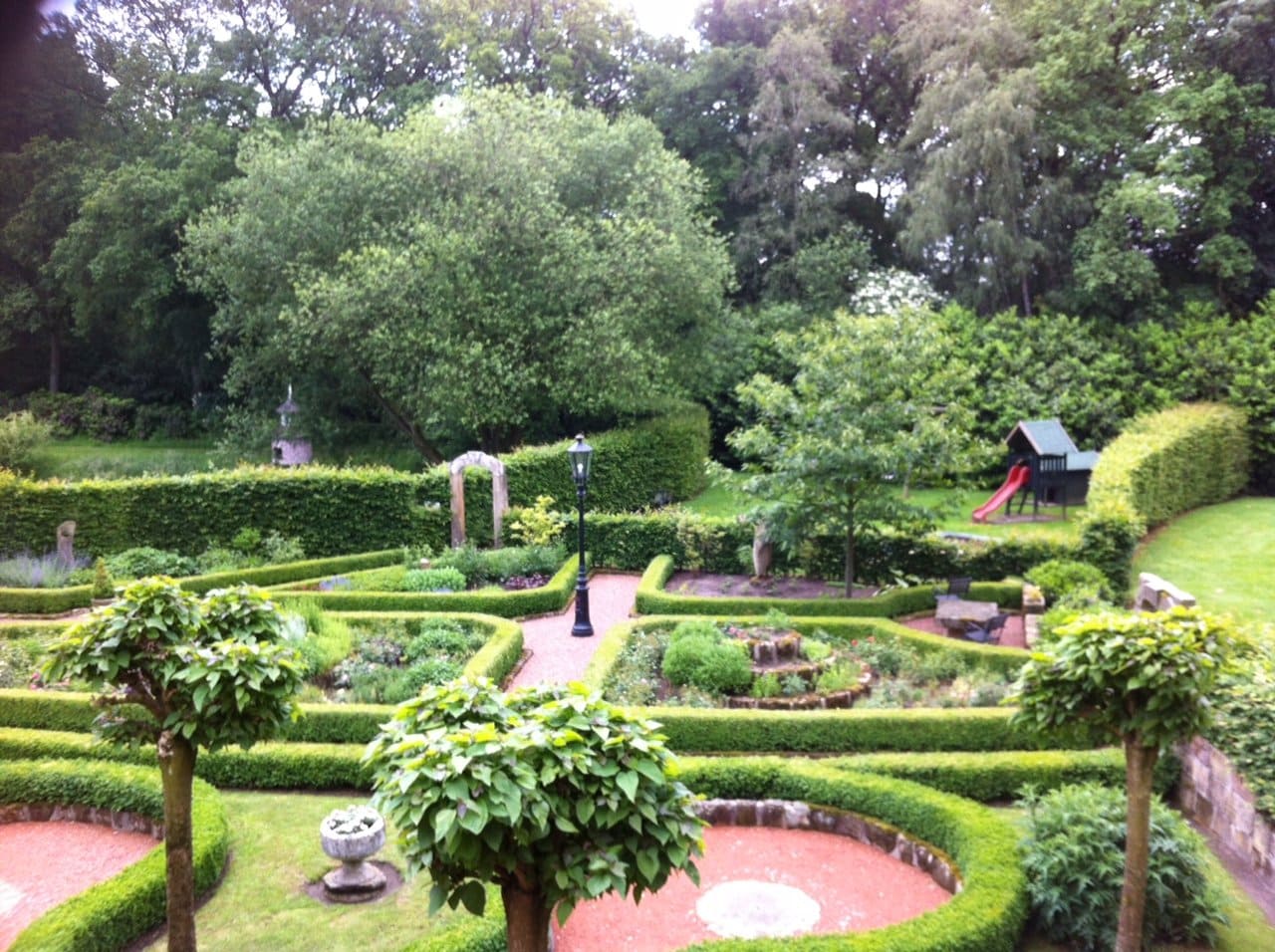 Ein Garten mit Bäumen und Sträuchern und einem Spielplatz im Hintergrund
