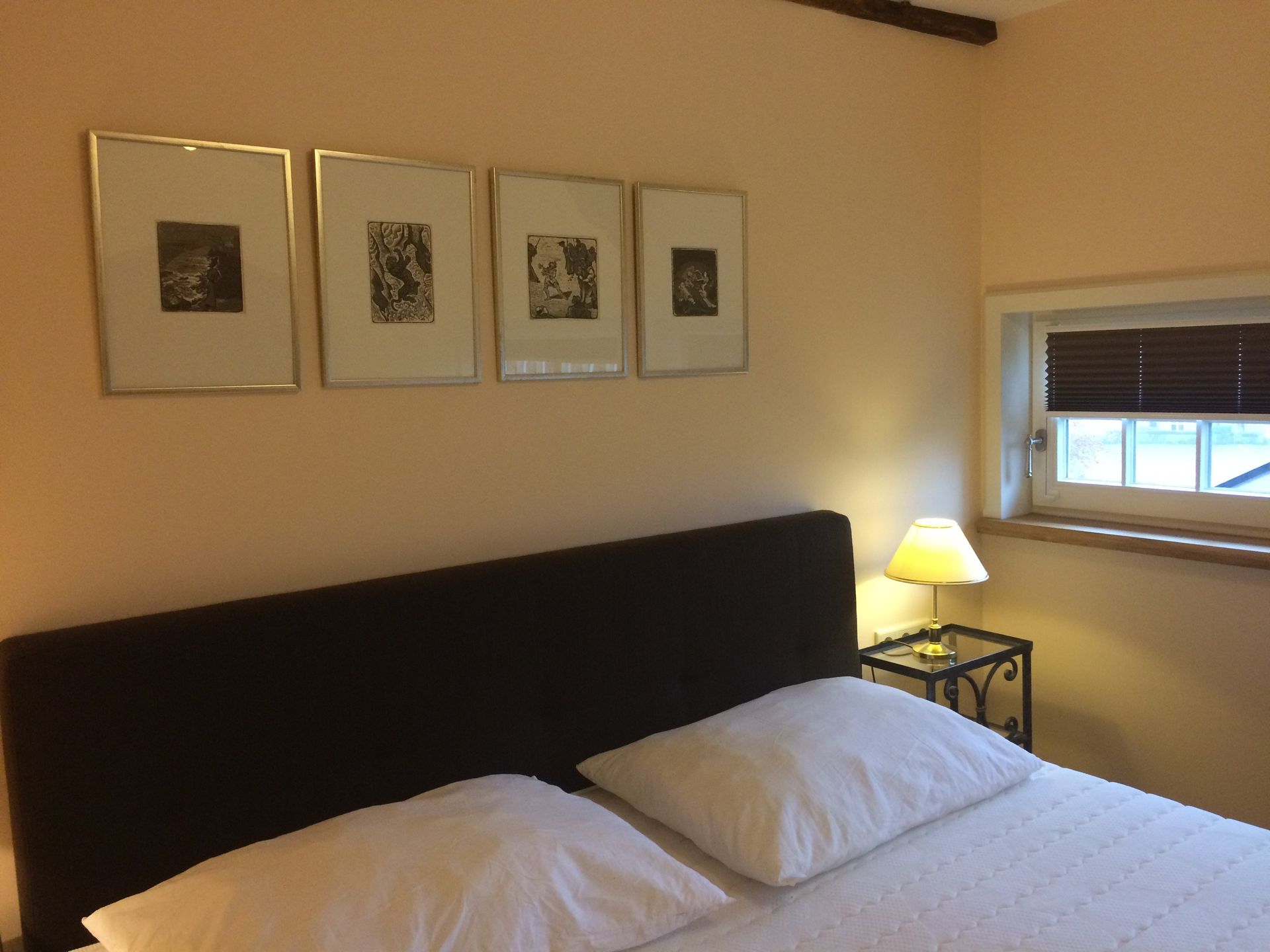 Een slaapkamer met een bed, lampen en schilderijen aan de muur