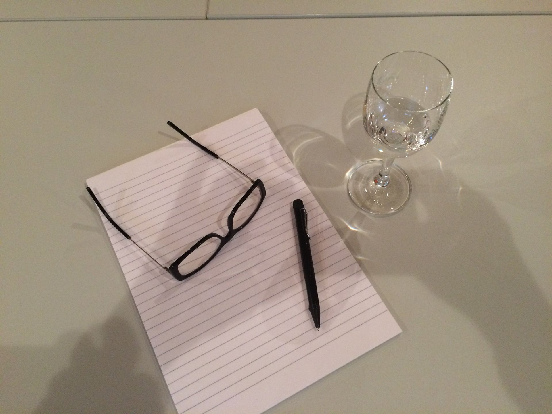 Een bril, een pen en een wijnglas op een stuk papier