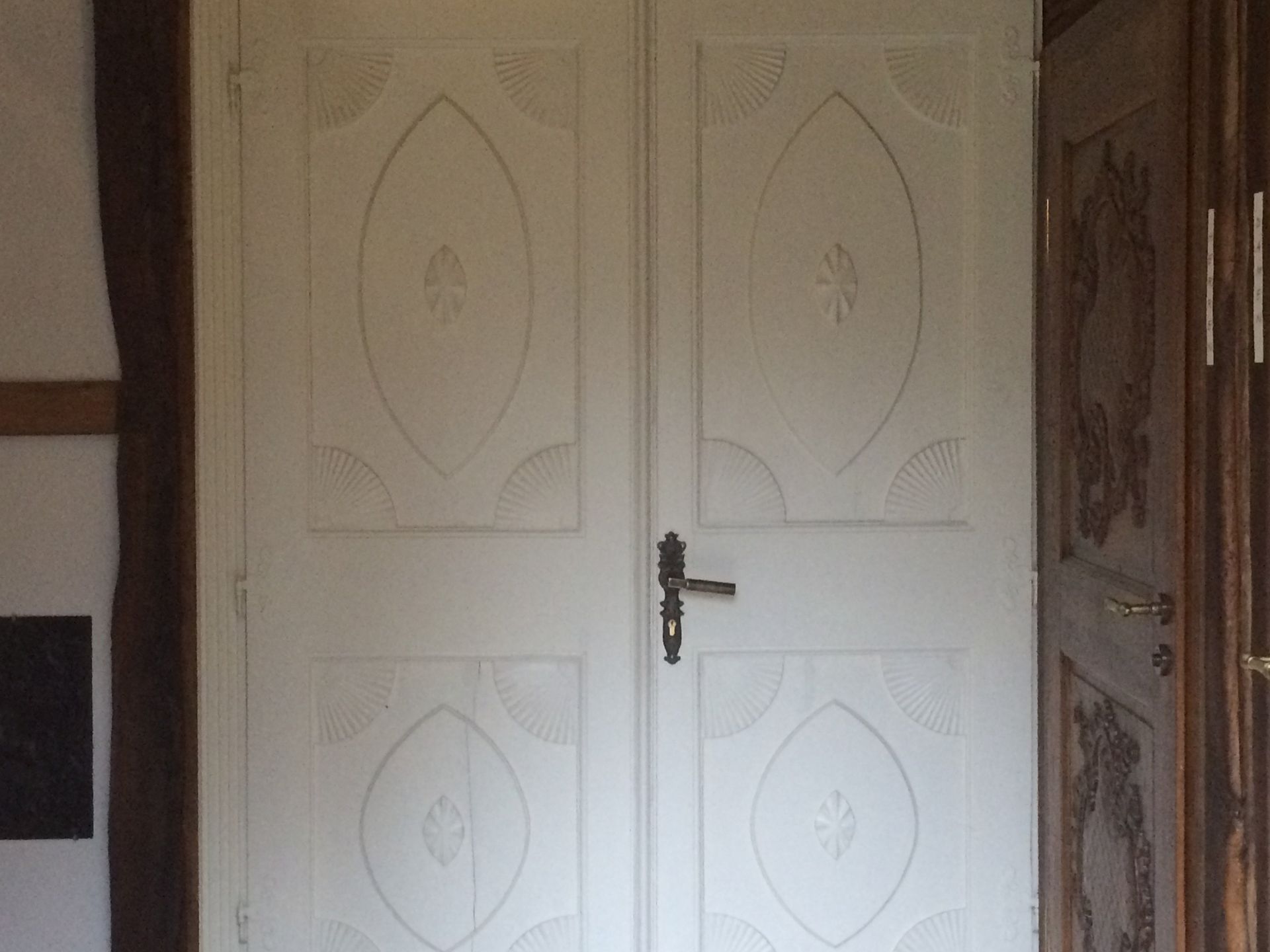 Een paar witte deuren met een zwarte klink in een kamer.