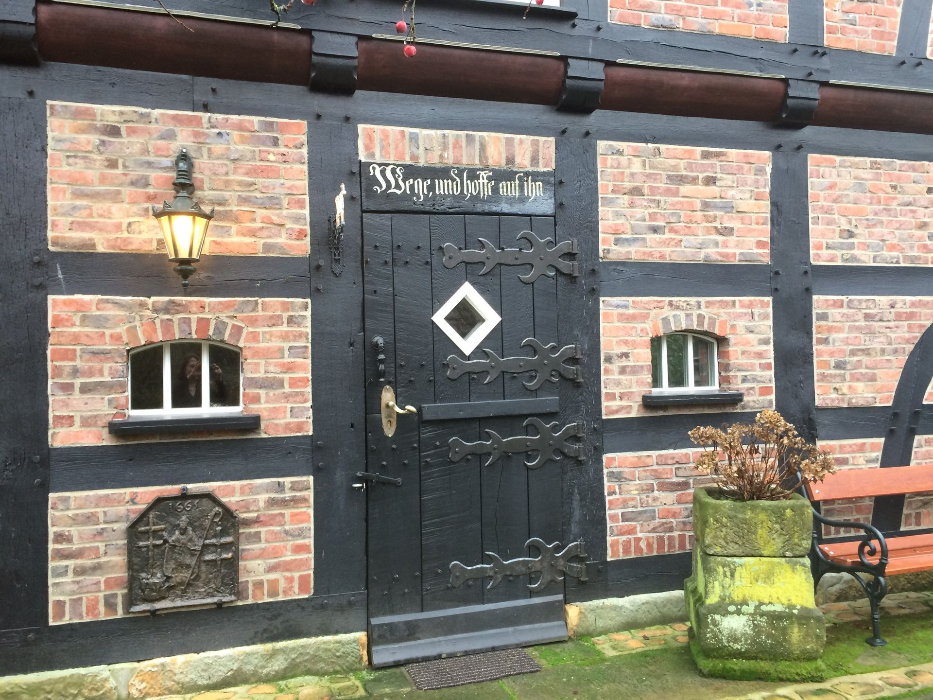 Een bakstenen gebouw met een zwarte deur en een bank ervoor