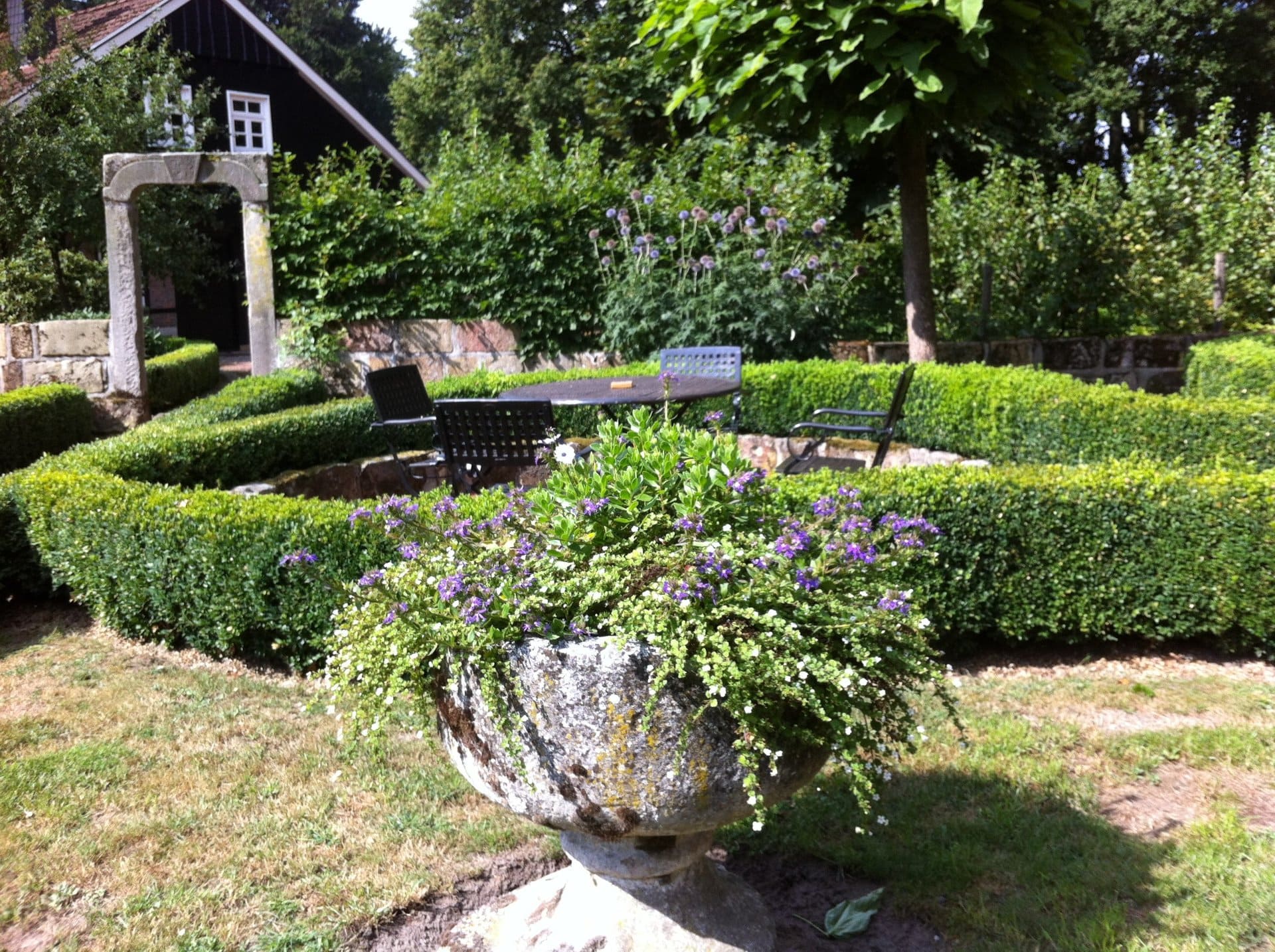 Ein Garten mit einem Tisch und Stühlen und einer Vase mit Blumen