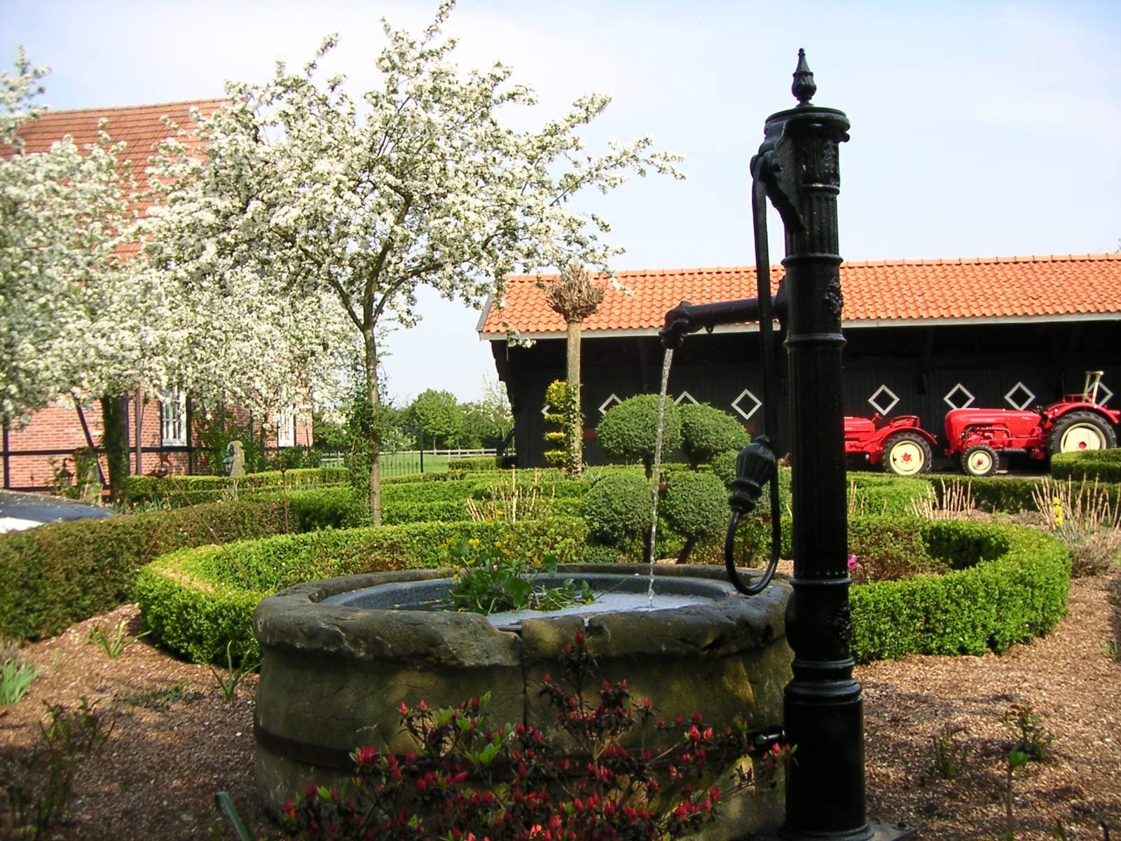 Ein Brunnen in einem Garten mit einem Traktor im Hintergrund