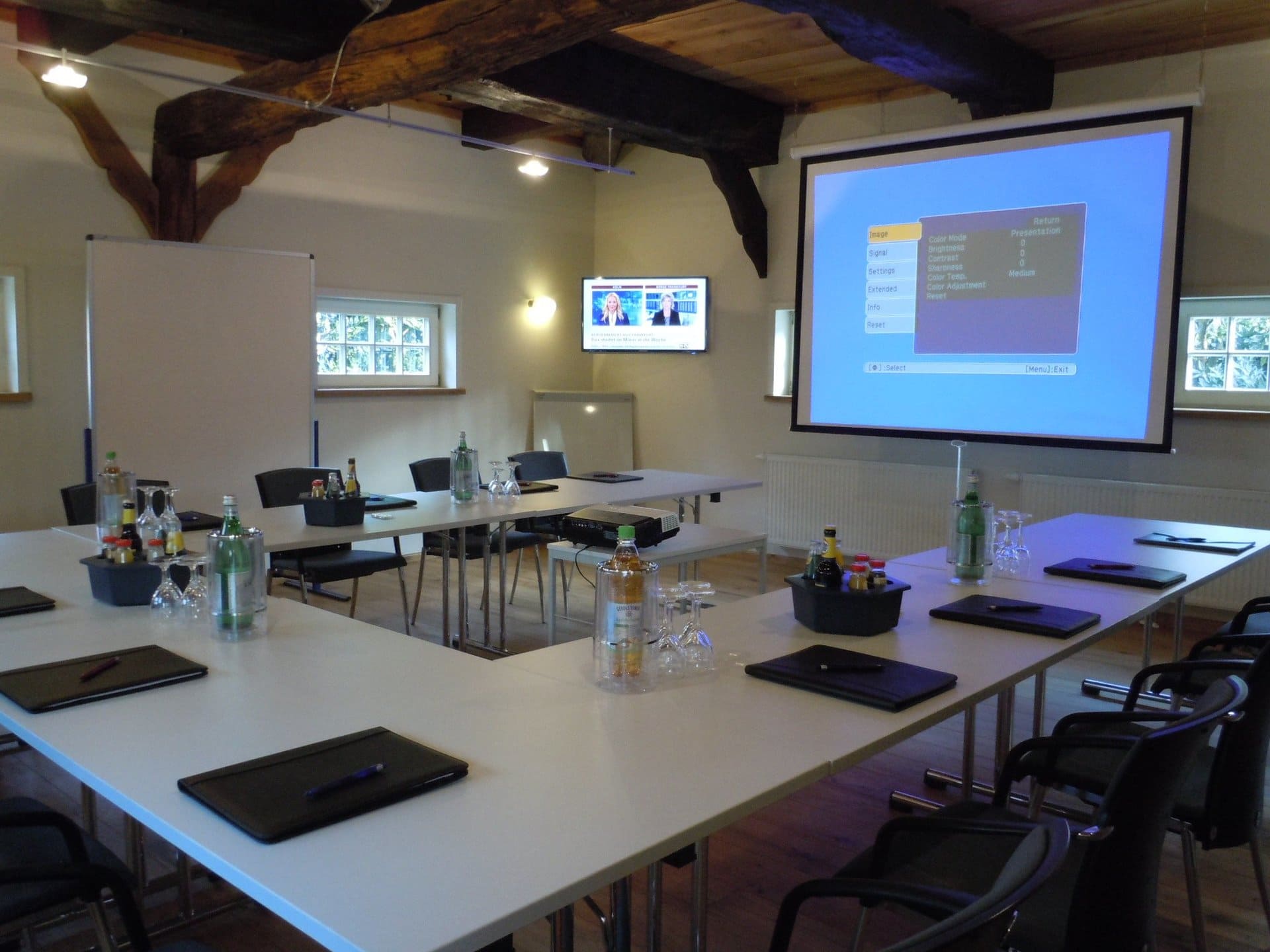 Ein Konferenzraum mit Tischen und Stühlen und einer Projektionsleinwand