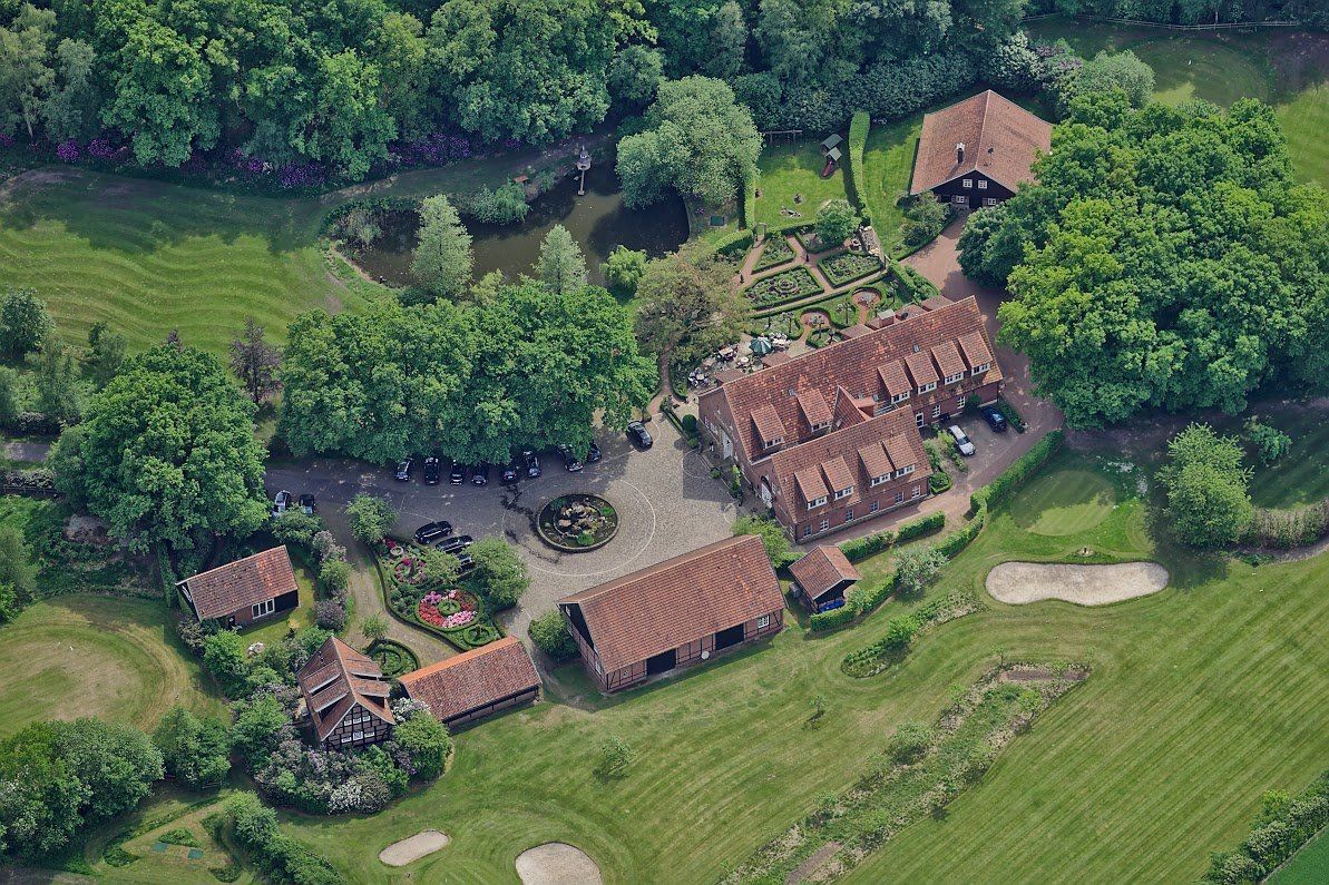 Een luchtfoto van een groot huis omgeven door bomen en gras.