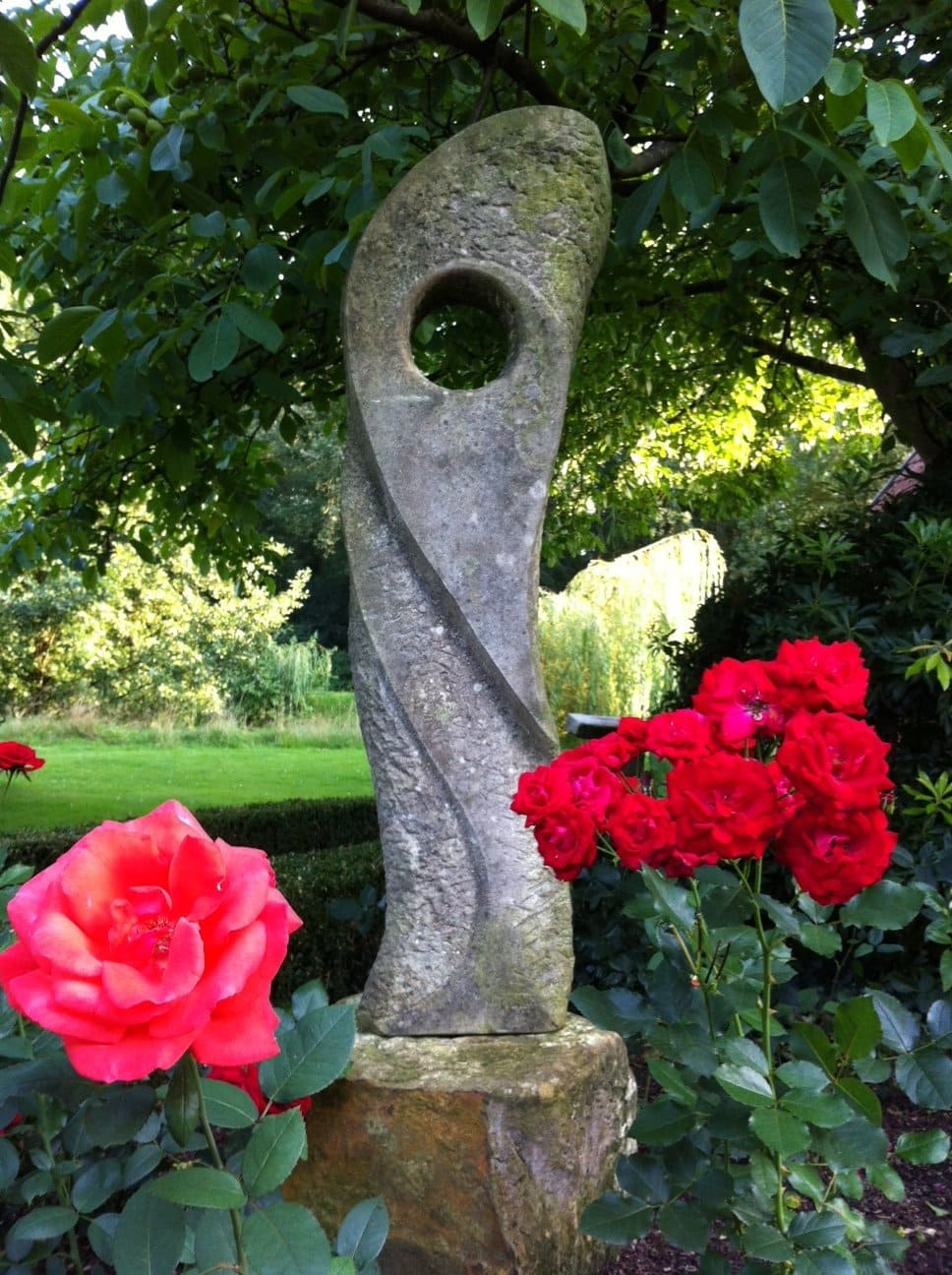 Eine Statue in einem Garten mit roten Rosen davor